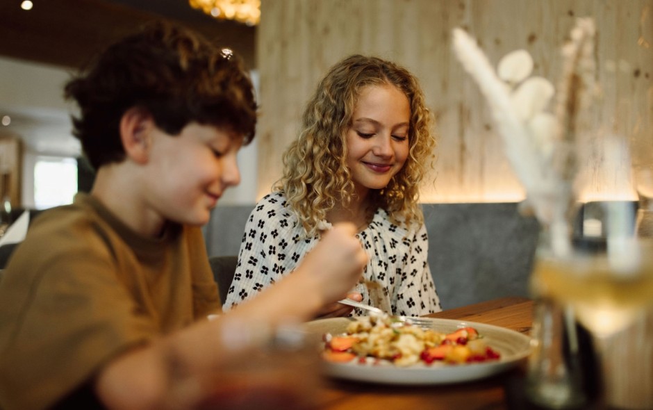 Zwei Kinder genie&szlig;en das Essen im Restaurant des Hotel Resl