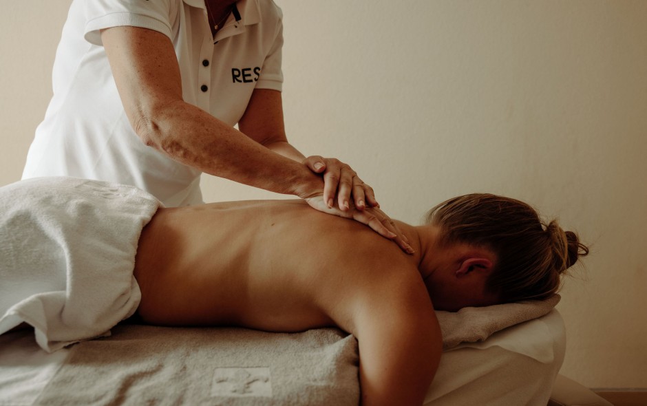 Gast erh&auml;lt eine wohltuende R&uuml;ckenmassage im Wellnessbereich des Hotel Resl Resort in Flachau